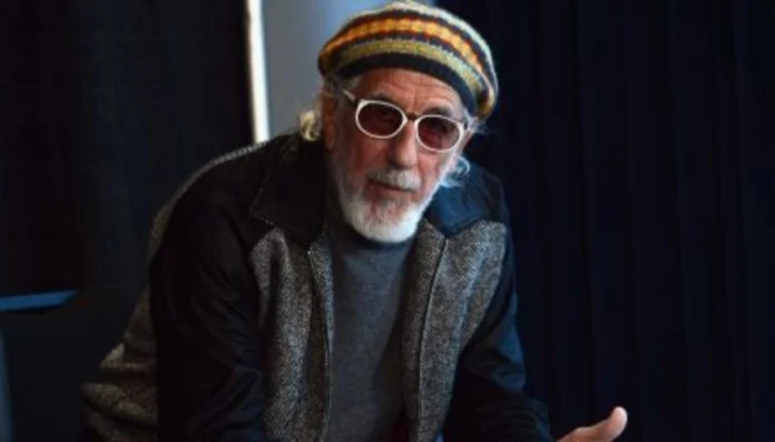 Lou Adler smiling courtside at a Lakers game, symbolizing his legacy and wealth—an iconic visual for understanding lou adler net worth.