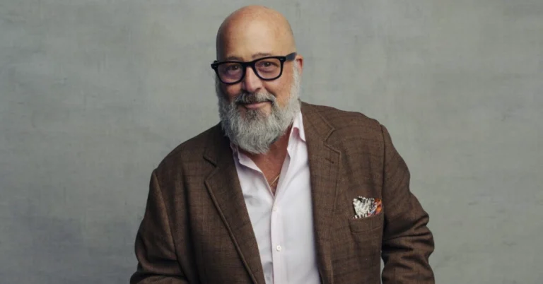 Andrew Zimmern smiling at a food market, showcasing his adventurous spirit as a chef and TV host known for exploring global cuisines.