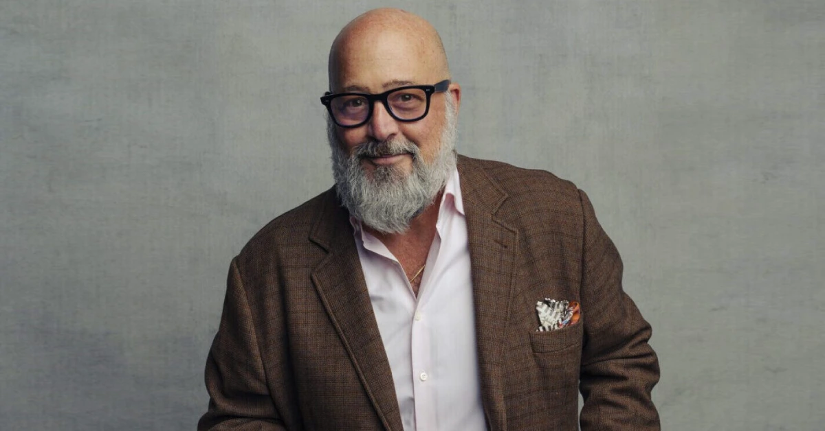 Andrew Zimmern smiling at a food market, showcasing his adventurous spirit as a chef and TV host known for exploring global cuisines.